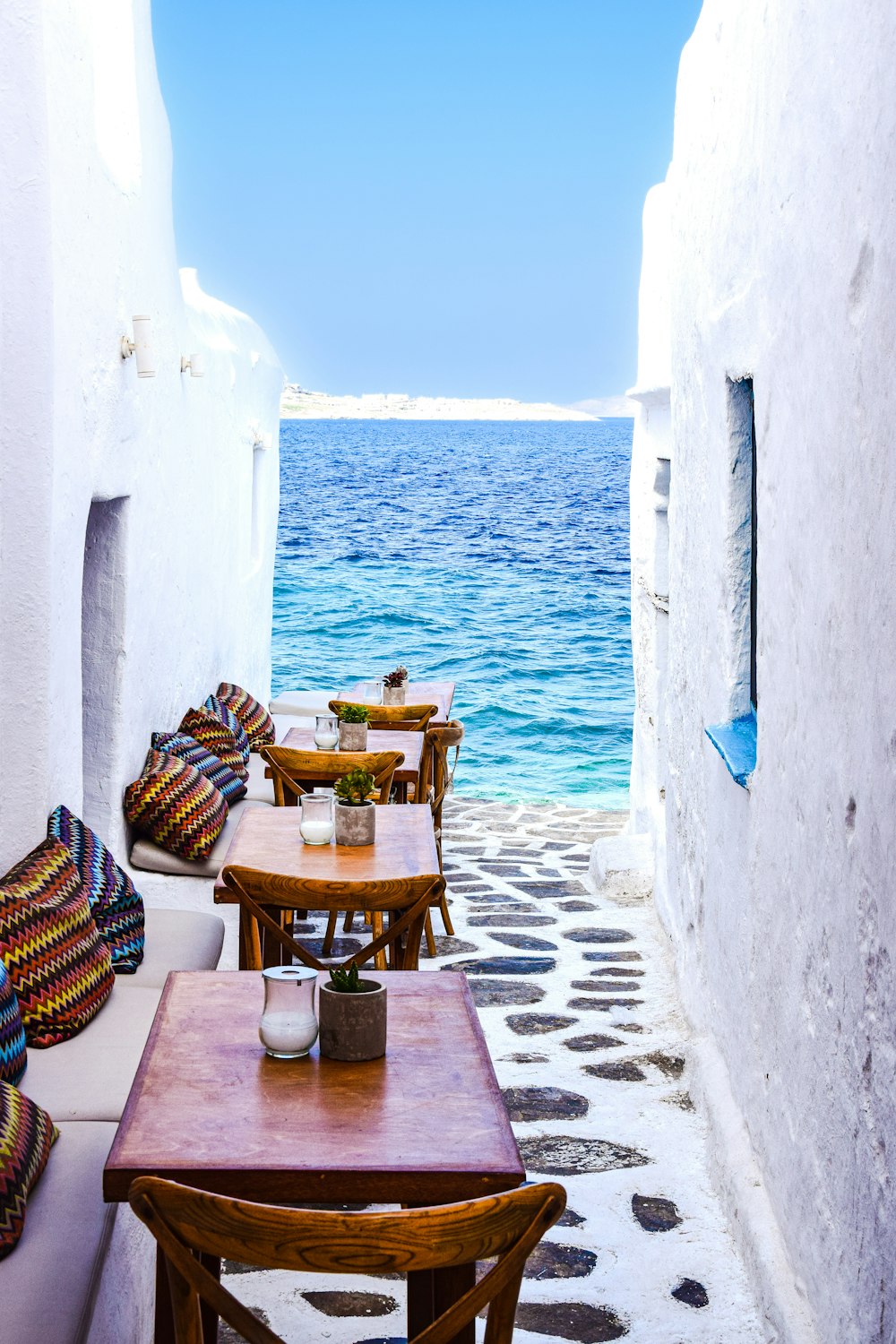 a patio with tables and chairs by the water