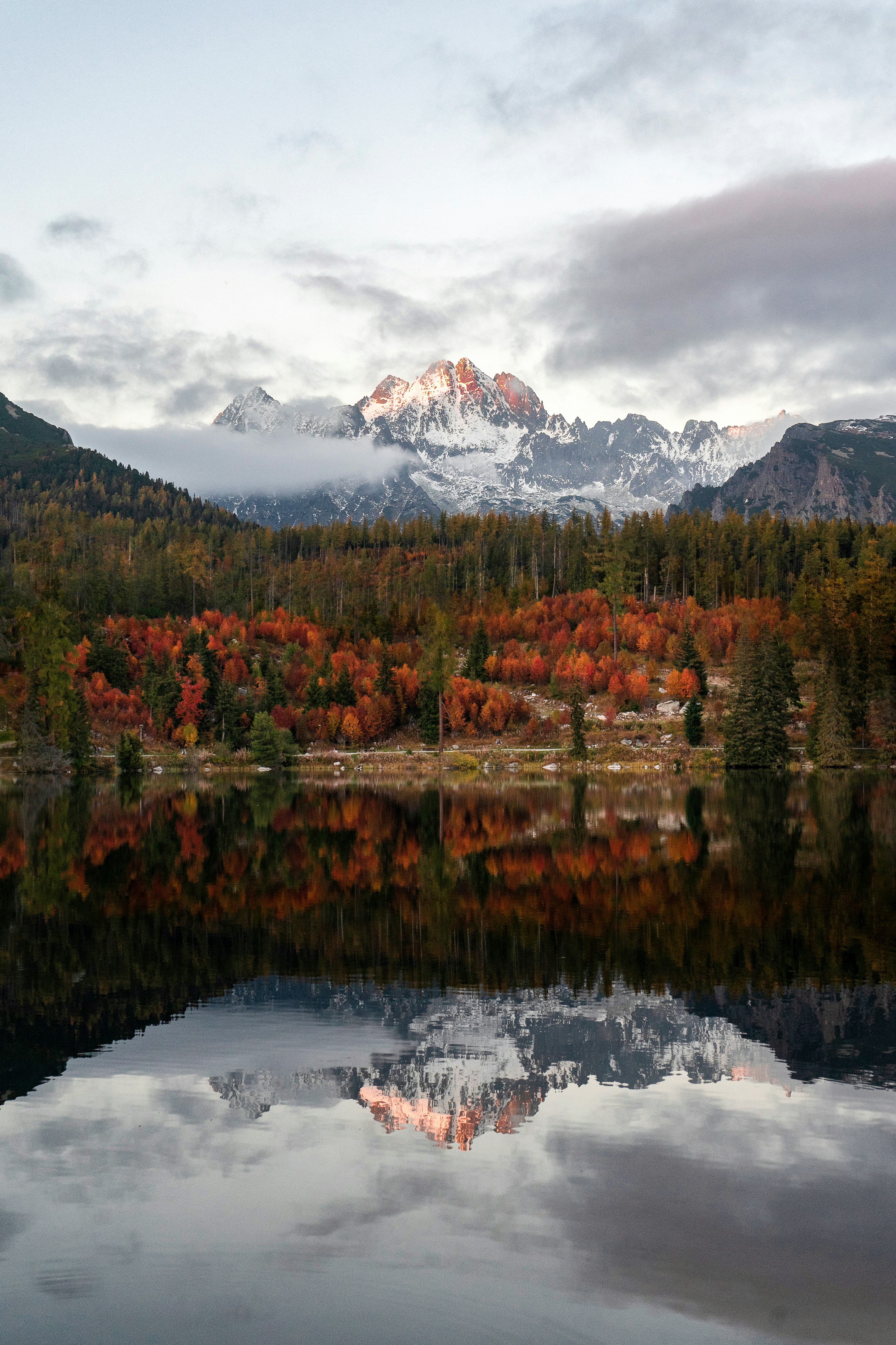 um lago com árvores e montanhas ao fundo