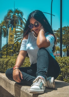 A stylish woman wearing a casual top and jeans in a sunny park.
