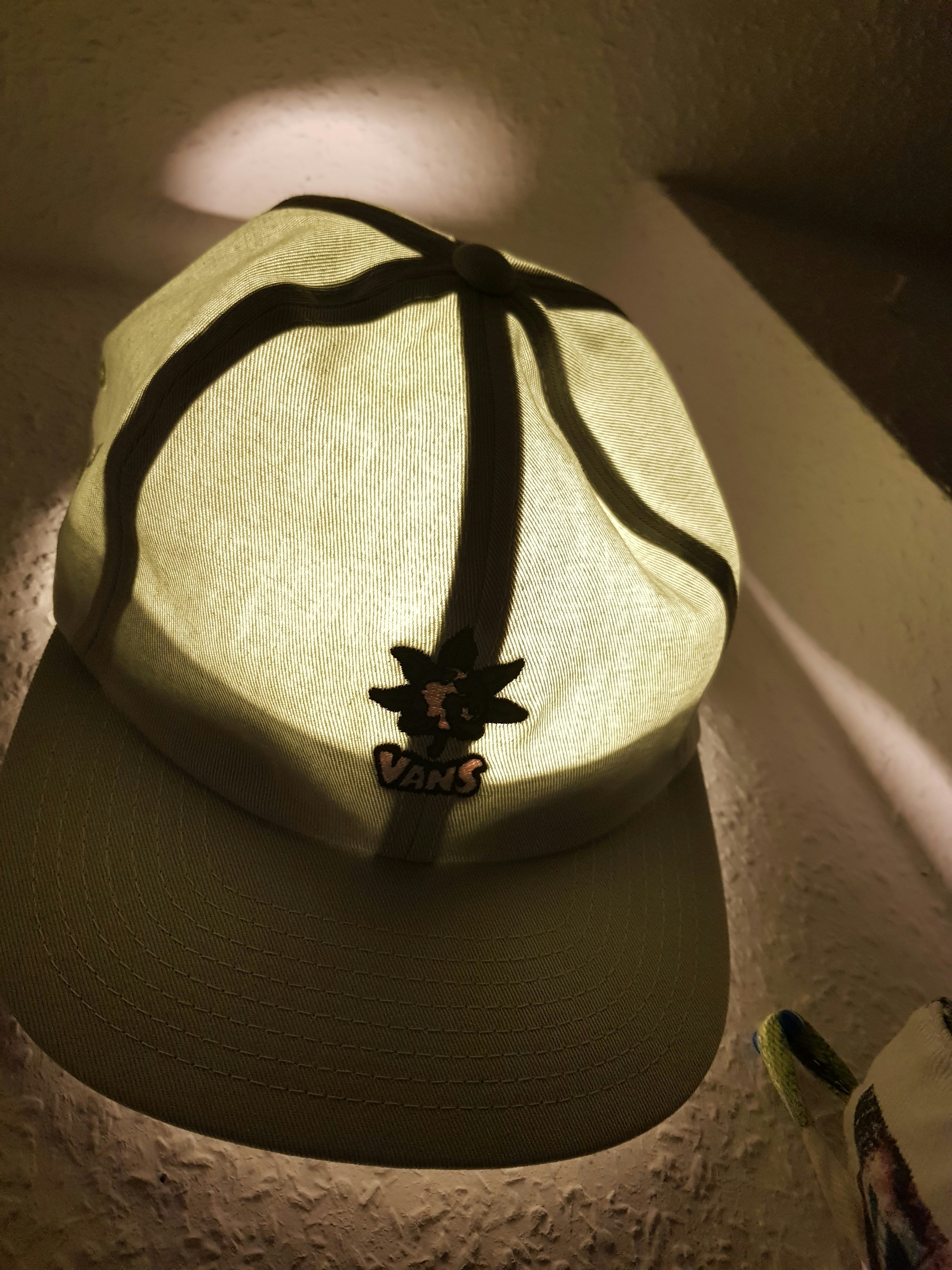 Black snapback cap with embroidered logo, dark background with soft spotlight