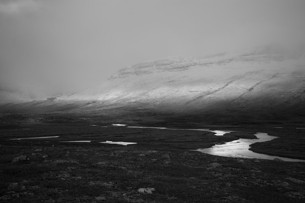 a black and white photo of a mountain range with a river running through it