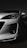 A white car is prominently displayed with a focus on its front headlight and sleek, aerodynamic design. The lighting accentuates the contours and details of the car against a dark background, giving it a dramatic and stylish appearance.