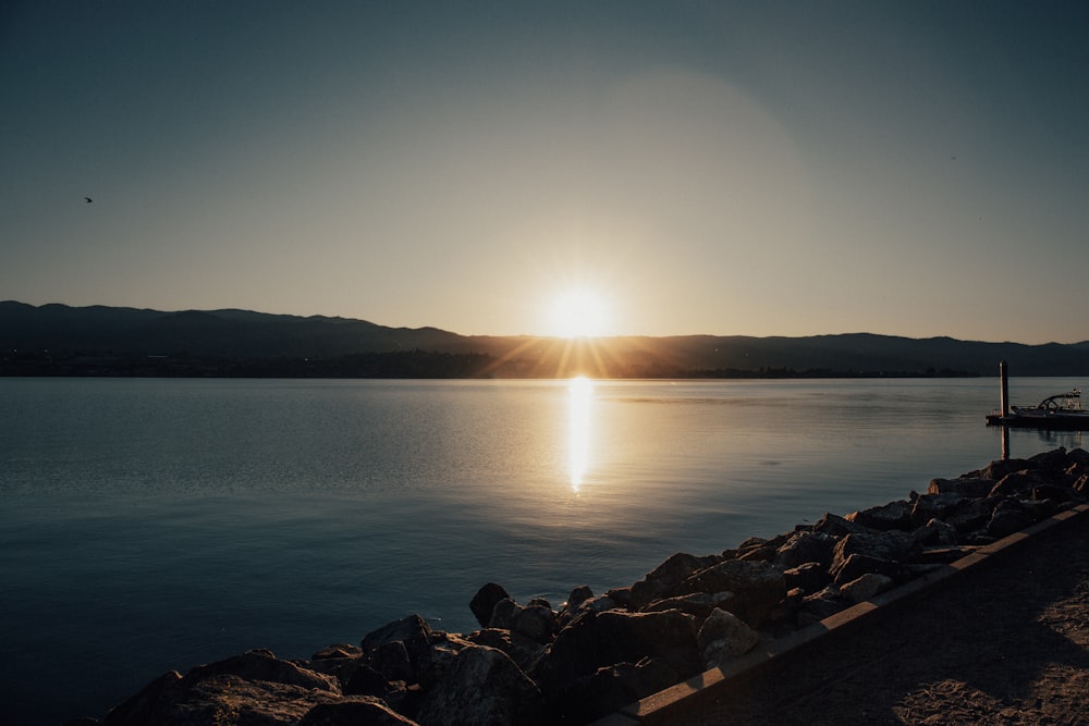 a body of water with a dock and a sunset