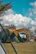 A family setting up a tent with camping equipment under a clear blue sky.