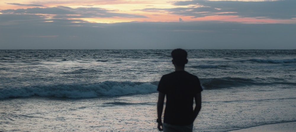 a person standing on a beach looking at the ocean