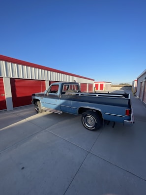 A navy blue a&l xpress transport truck parked at the Brookshire warehouse under a clear sky.