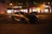 A sleek security vehicle patrolling a quiet, well-lit commercial area at dusk.