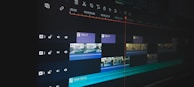 A digital video editing timeline displayed on a monitor screen, featuring multiple layers and tracks. Various clips are arranged with timelines visible, along with icons for audio and video settings. The user interface includes text and video clips organized in a sequence, indicating a detailed editing process.