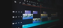 A digital video editing timeline displayed on a monitor screen, featuring multiple layers and tracks. Various clips are arranged with timelines visible, along with icons for audio and video settings. The user interface includes text and video clips organized in a sequence, indicating a detailed editing process.