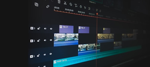 A digital video editing timeline displayed on a monitor screen, featuring multiple layers and tracks. Various clips are arranged with timelines visible, along with icons for audio and video settings. The user interface includes text and video clips organized in a sequence, indicating a detailed editing process.