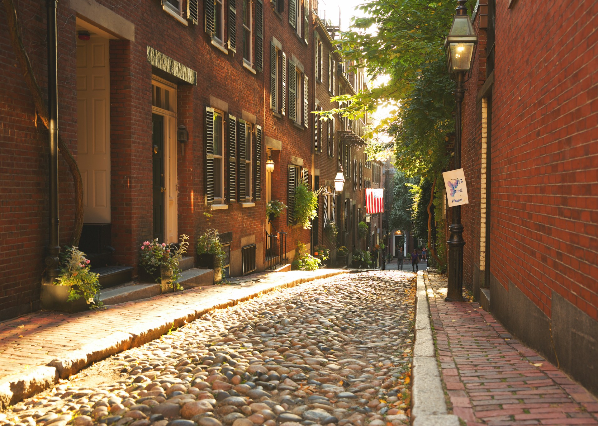 a cobblestone street with brick buildings and a lamp post