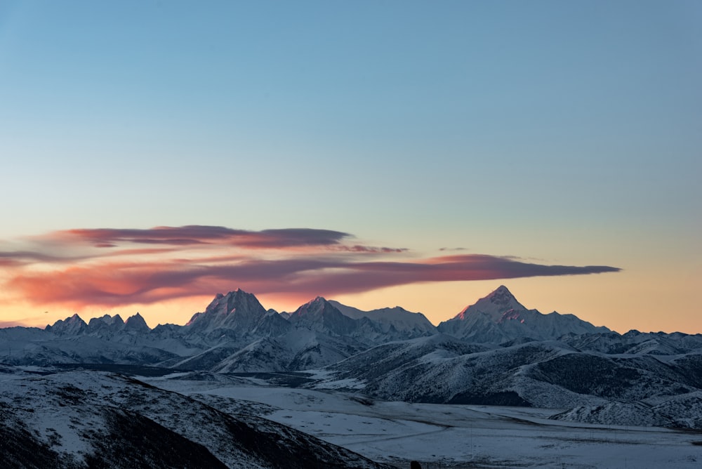 a snowy landscape with mountains in the background