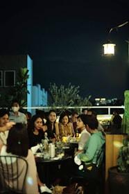 A cozy rooftop setting with a small group engaged in deep conversation under warm lights.