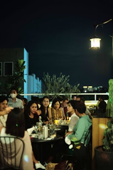 Guests enjoying drinks and conversation on the cozy rooftop seating area overlooking NYC skyline at dusk.