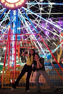 A couple striking playful poses as they spin slowly on the 360 photobooth at a lively party.