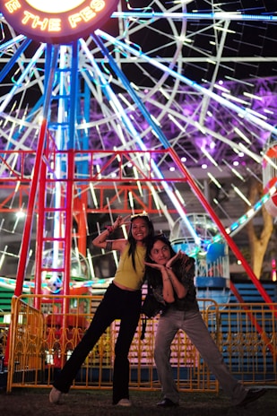 A couple striking playful poses as they spin slowly on the 360 photobooth at a lively party.