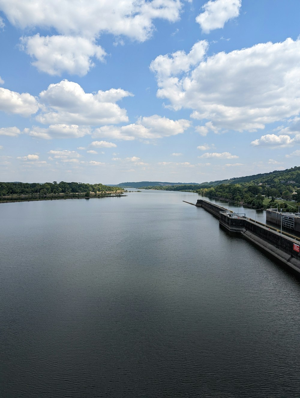 a body of water with a dock and trees on the side