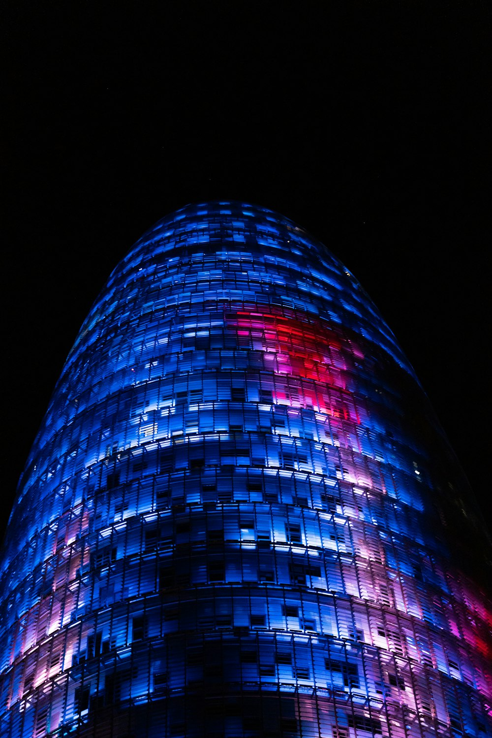 a tall building with many windows with Torre Agbar in the background