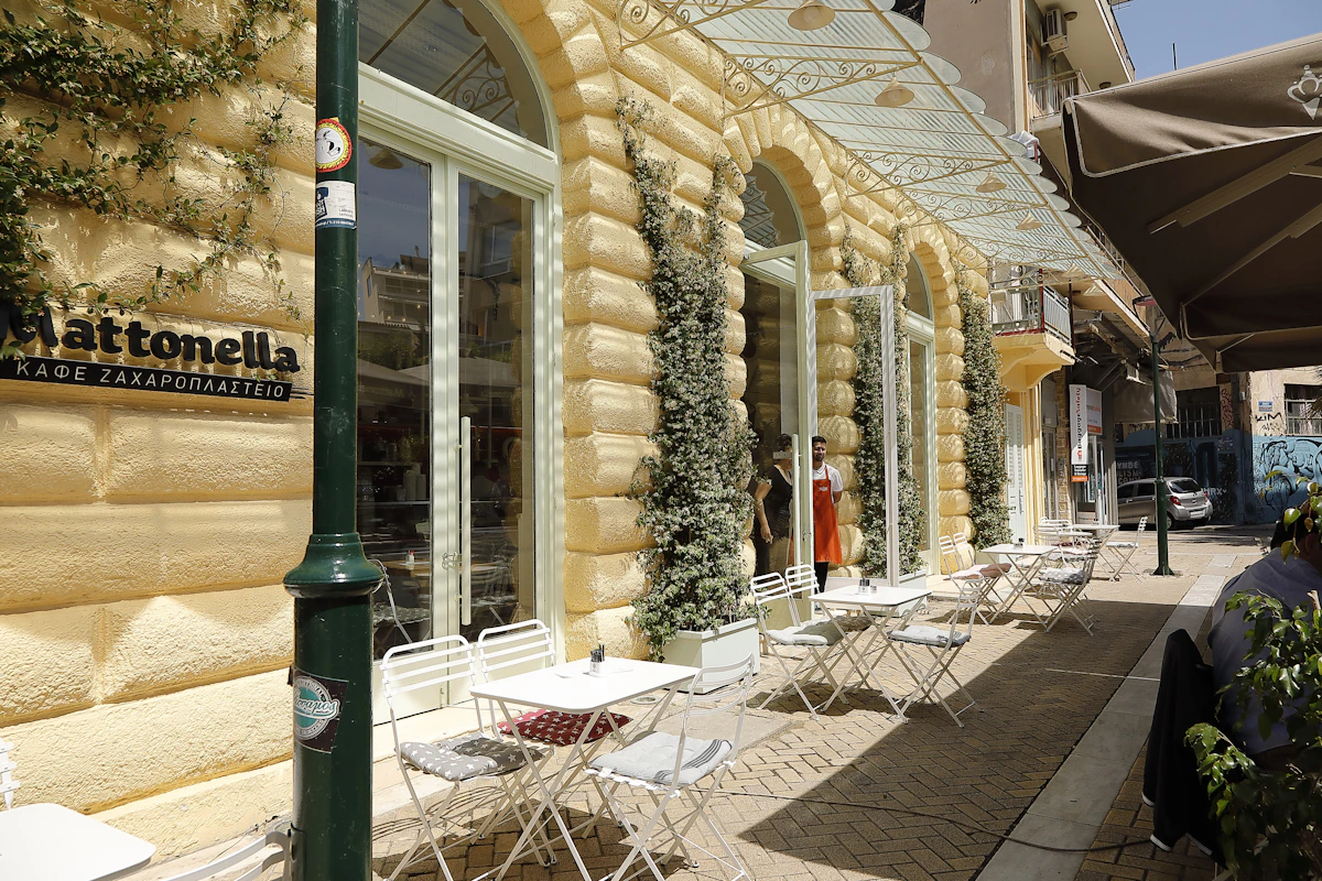 Outdoor café tables beneath old buildings and greenery in Psirri, Athens