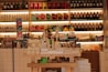 A well-stocked shop shelf filled with various beauty and wellness products, including bottles, boxes, and jars. The shelves are neatly organized with different color-coded sections containing skincare bottles, soaps, and colorful packaging. The lighting is warm and inviting.