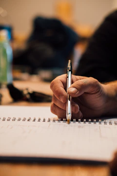 A close-up of a hand holding a pen over a leadership workbook filled with notes.