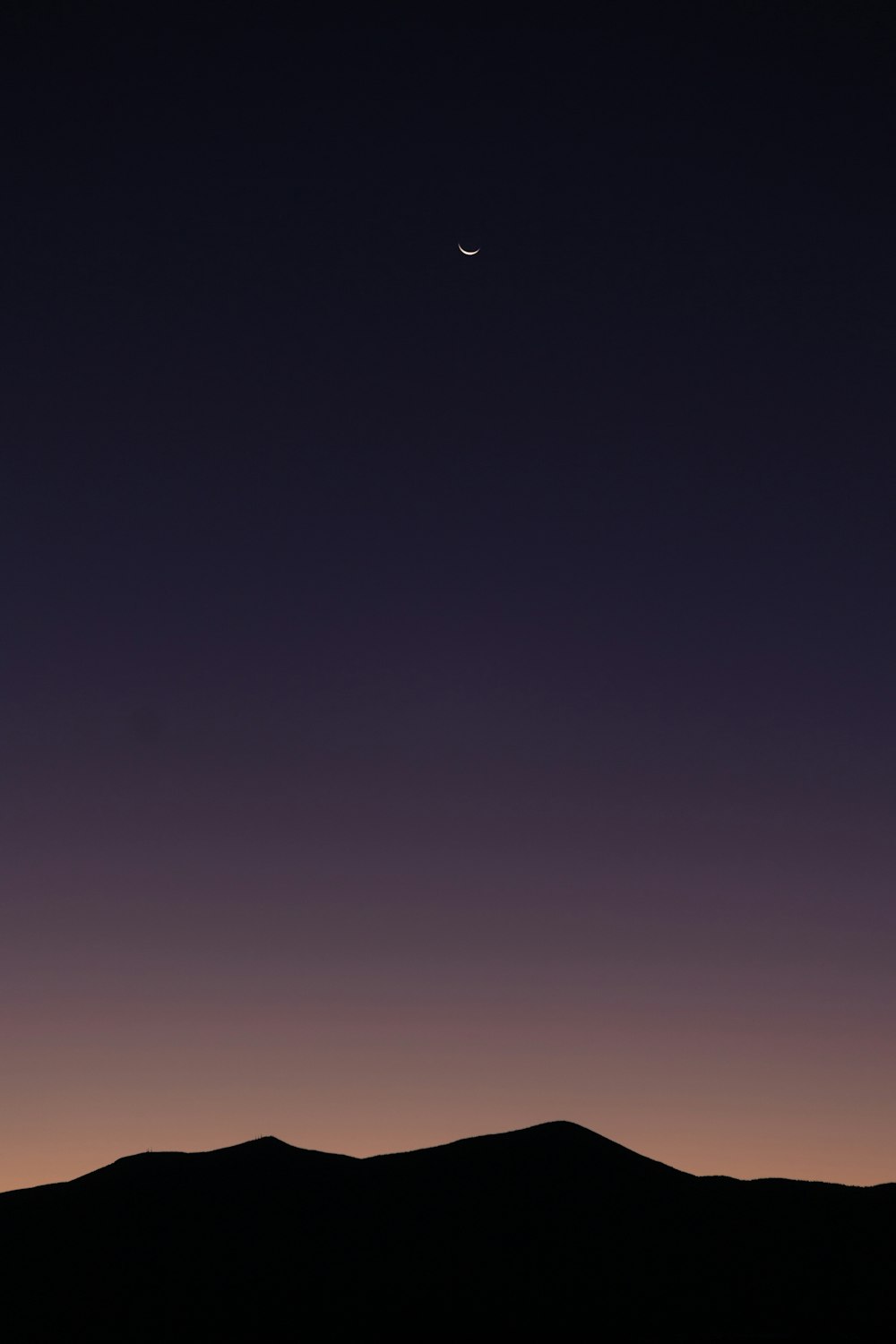 a mountain with a moon in the sky