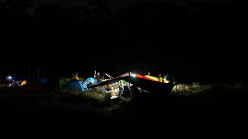 Nighttime festival scene with colorful lights and camping tents.