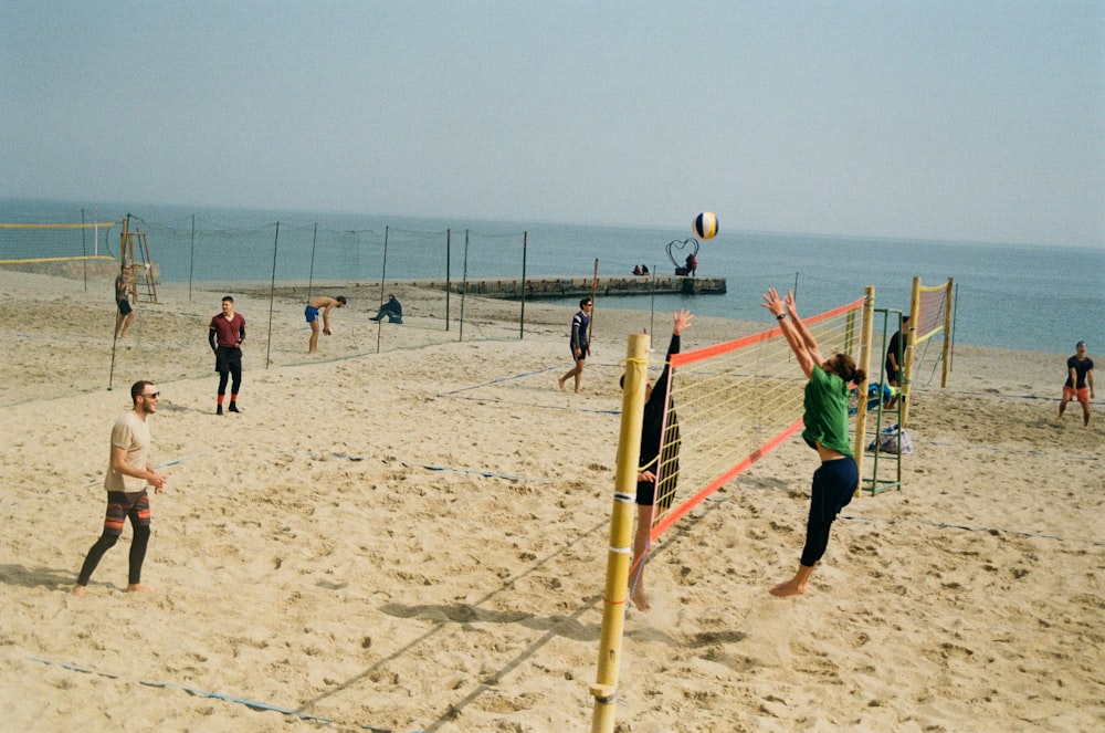 a group of people playing volleyball on a beach