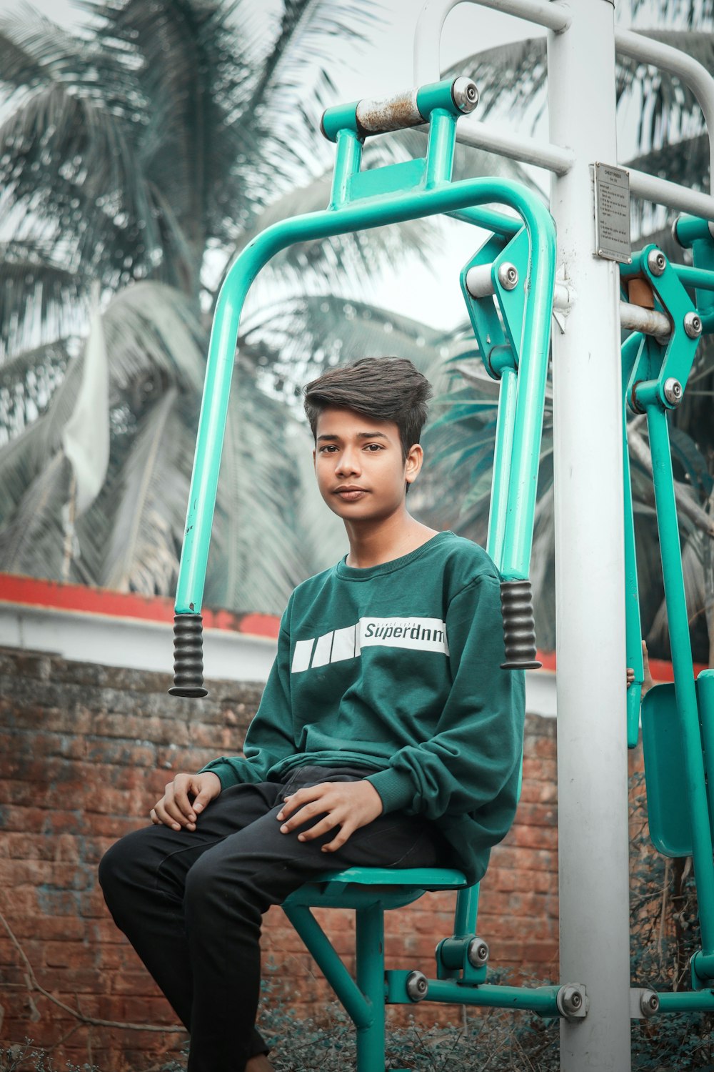 a boy sitting on a green slide