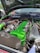 A car engine with a vibrant green valve cover and various components, including hoses and wires. The engine bay has a large, black itg air filter and shiny metallic parts. The hood is open, revealing a clean and well-organized setup.