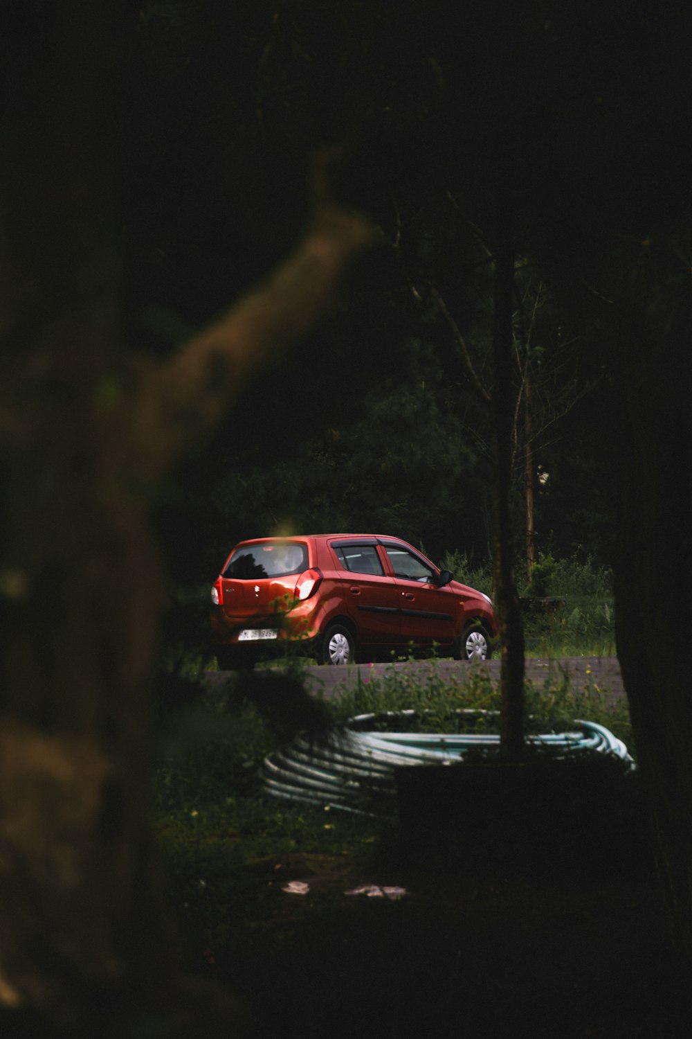 a red car parked in a wooded area