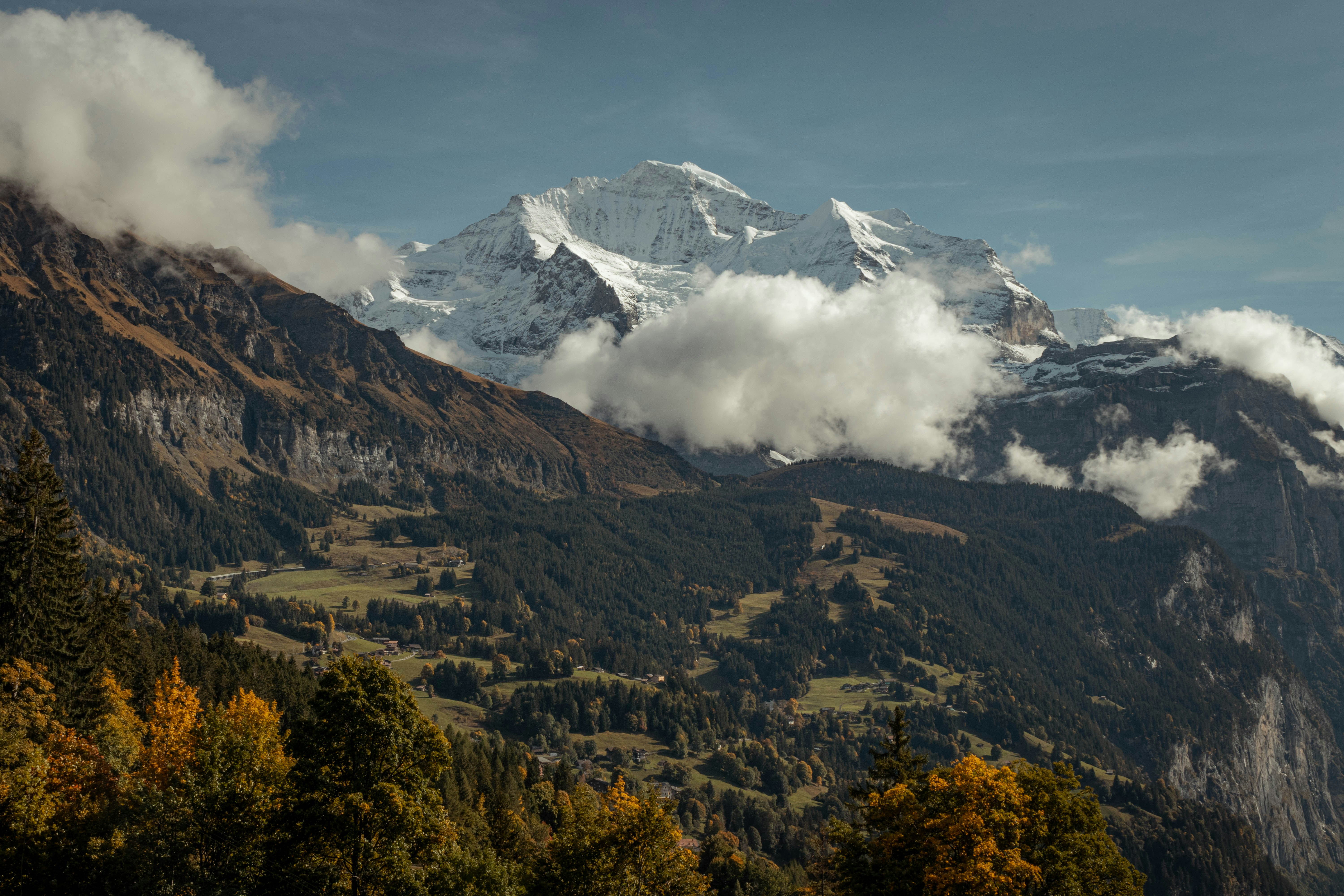 a mountain with snow, Impressive views over Wengen Switzerland during fall season, trees changing color and new layer of snow on Jungfrau mountain