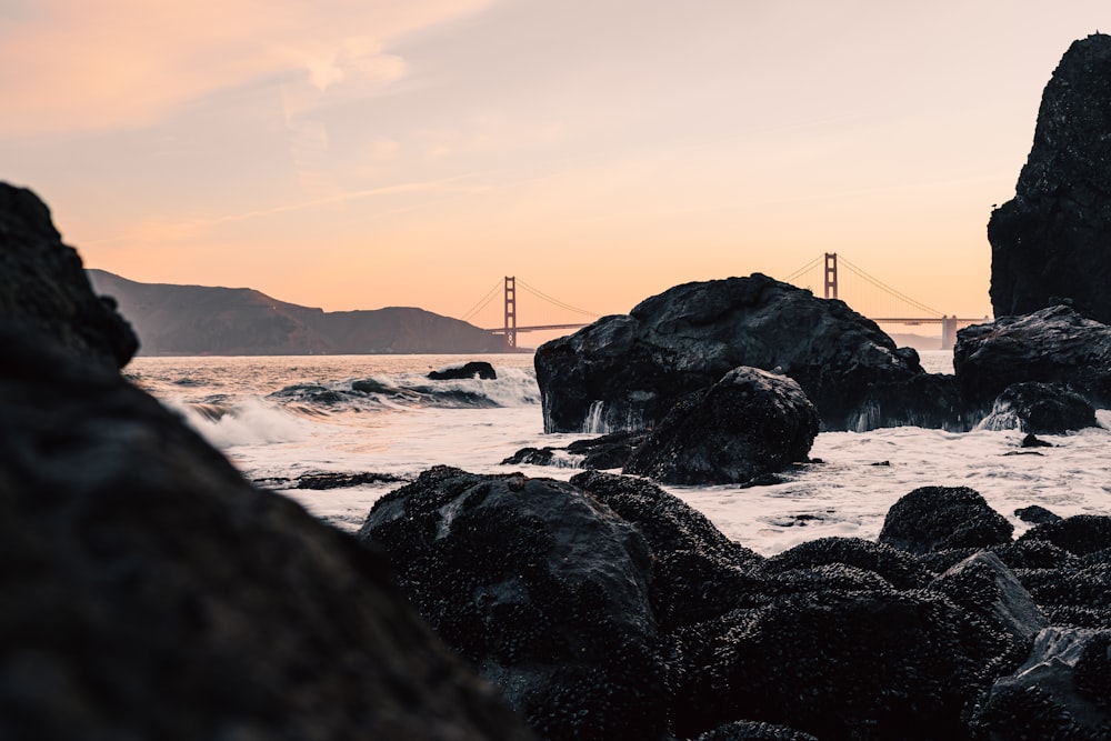 a rocky beach with a bridge in the background