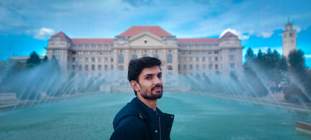 a man standing in front of a fountain and a large building