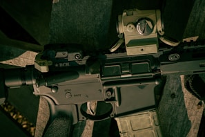 An AR-15 rifle outfitted with custom accessories resting on a wooden bench