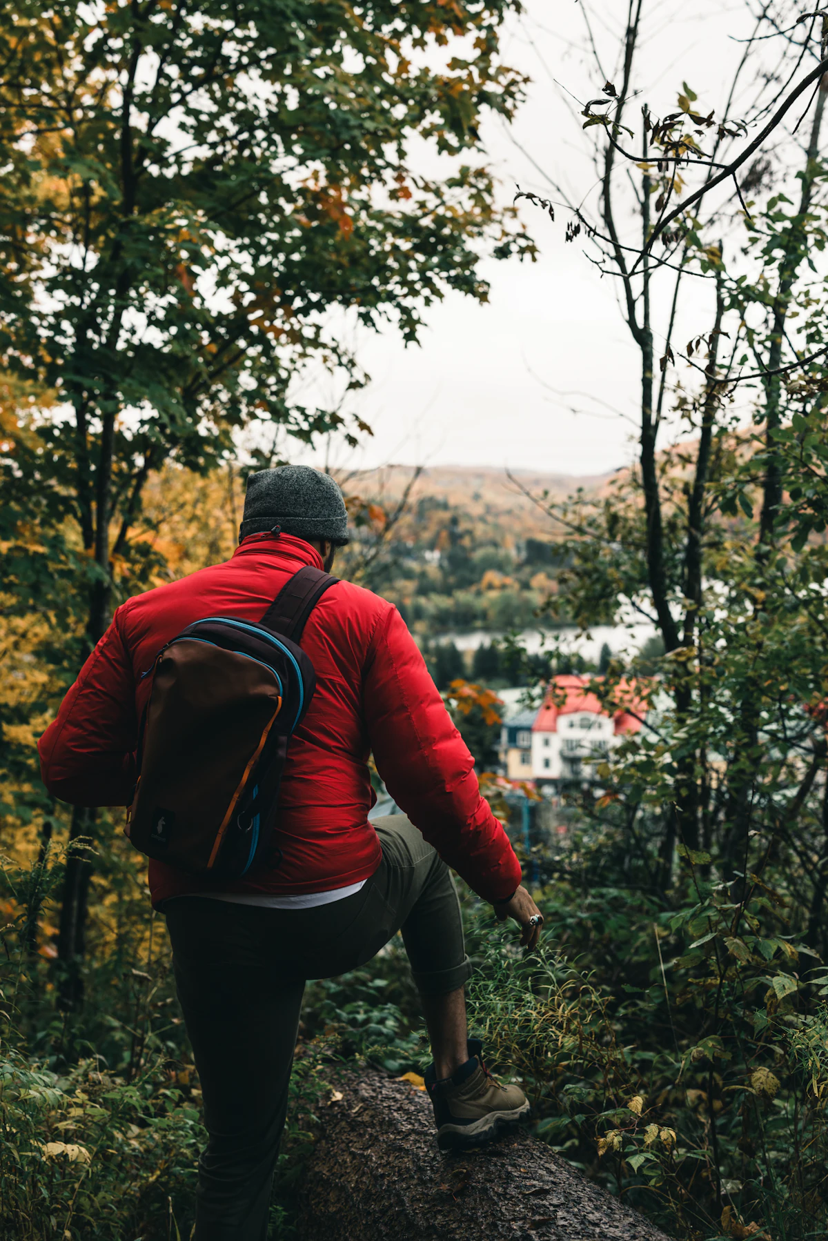 A hiker in a red jacket on a forest trail above the Mont-Tremblant village in autumn