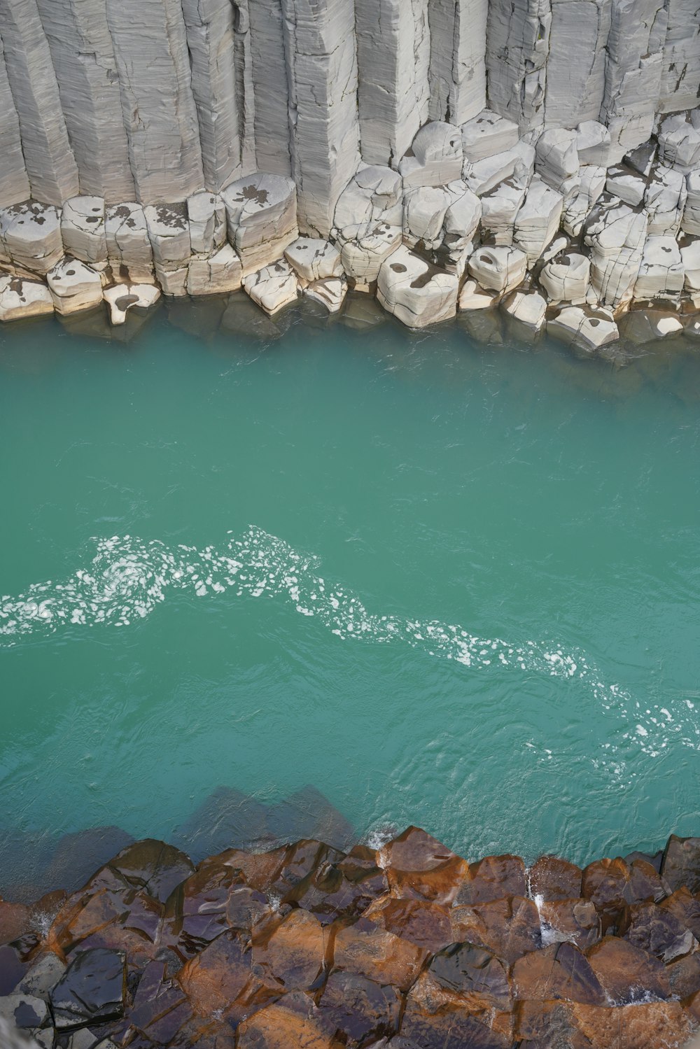 a body of water with rocks and a large stack of rocks