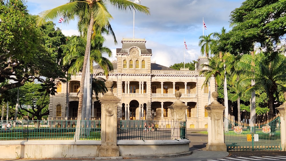 Iolani Palace with palm trees and a fence around it