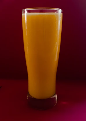 A vibrant glass of orange punch glowing against the dark café backdrop