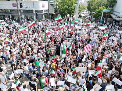 Wide shot of thousands of Iranians gathered peacefully in a city square for a national protest.
