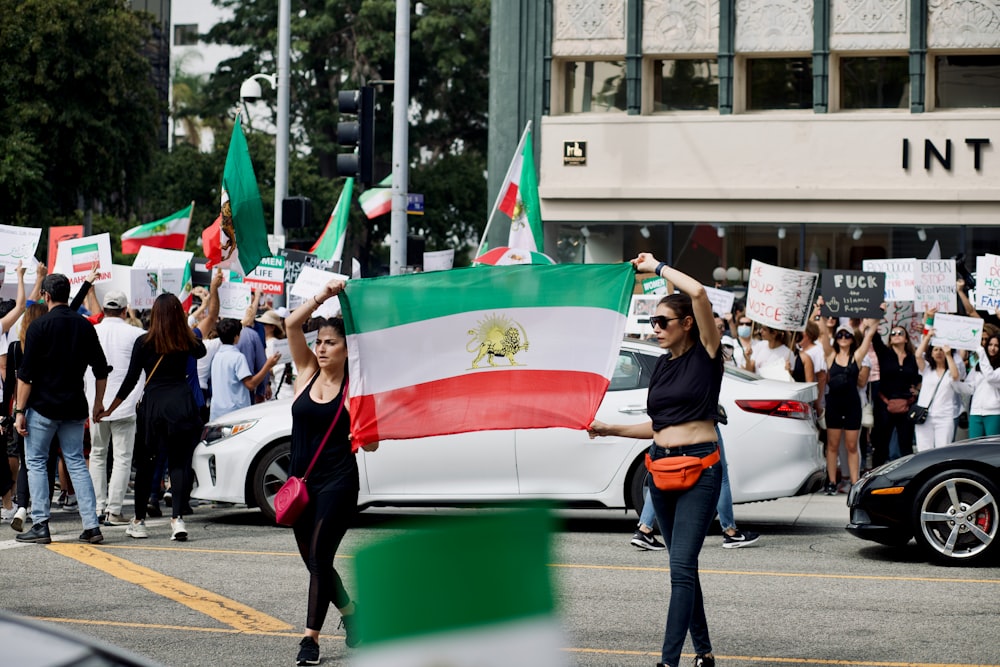 a group of people holding flags and walking on the street