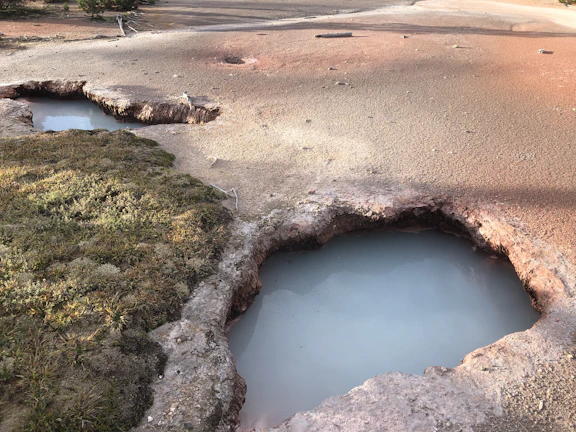 A barren landscape scarred by deep lithium excavation pits under a neon-lit night sky