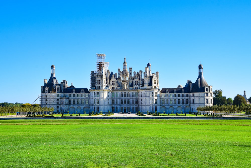 um grande edifício com um gramado em frente a ele com o Château de Chambord ao fundo