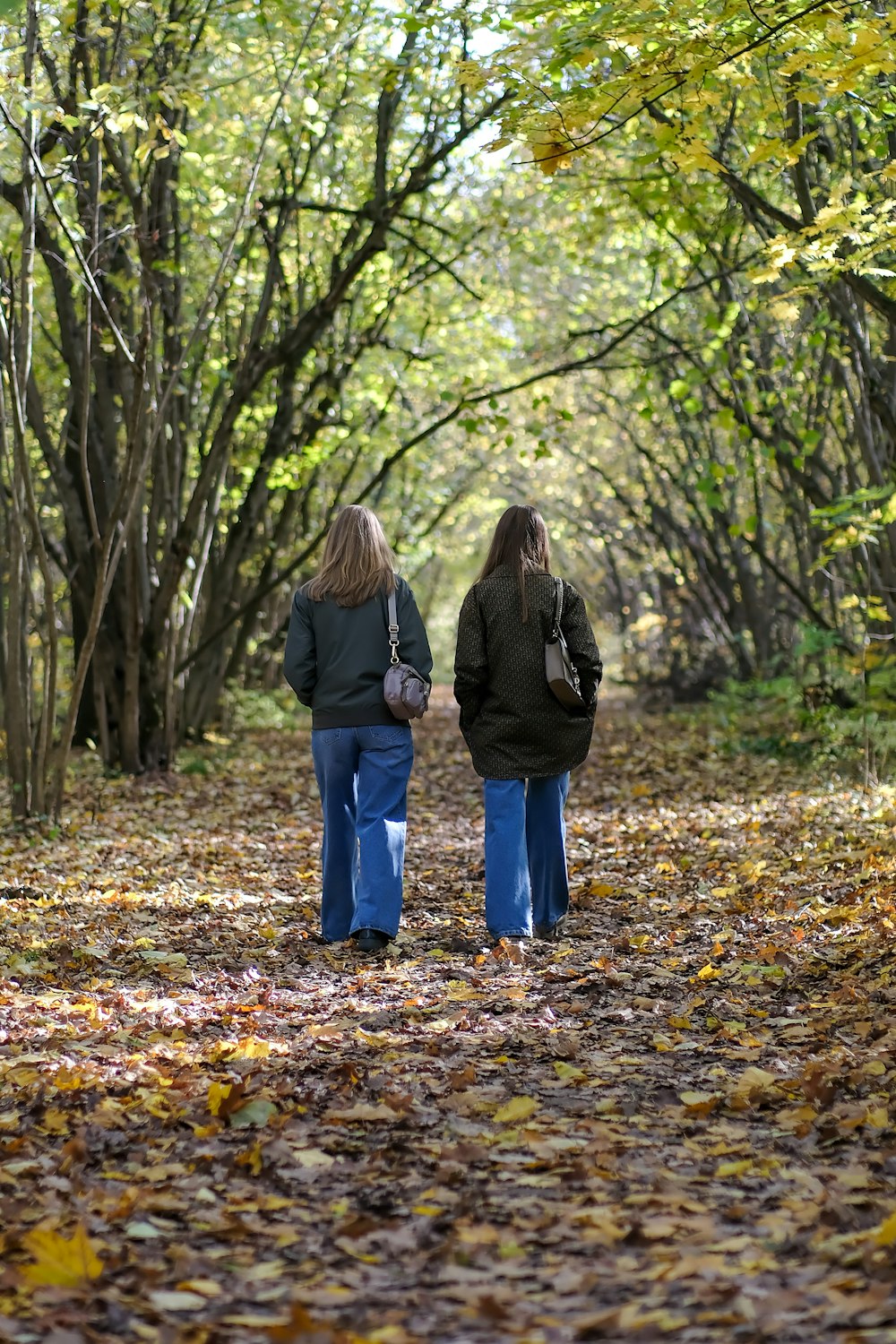 two women walking on a path in the woods