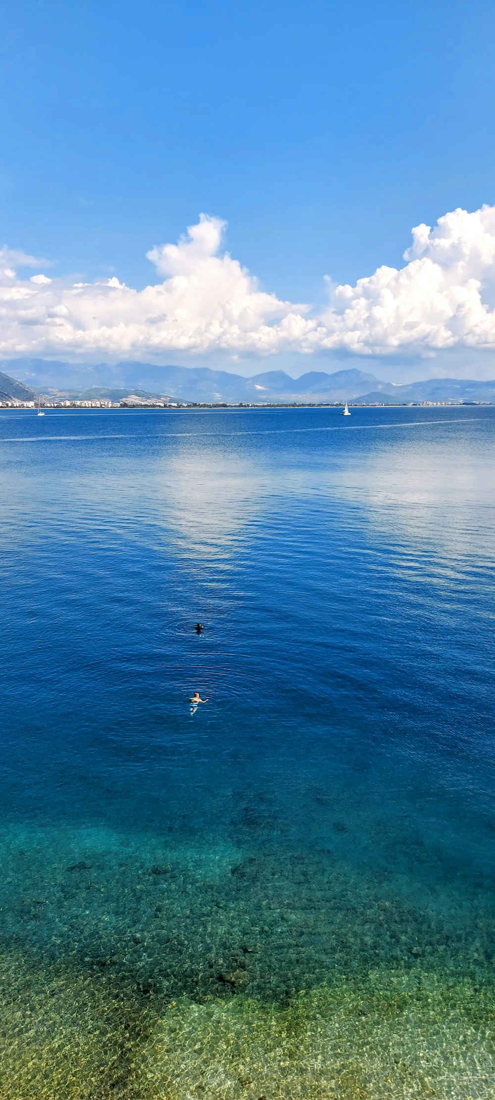 a body of water with boats in it and mountains in the background