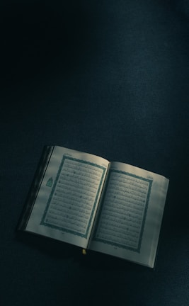 An open book with Arabic lyrics and musical instruments nearby.