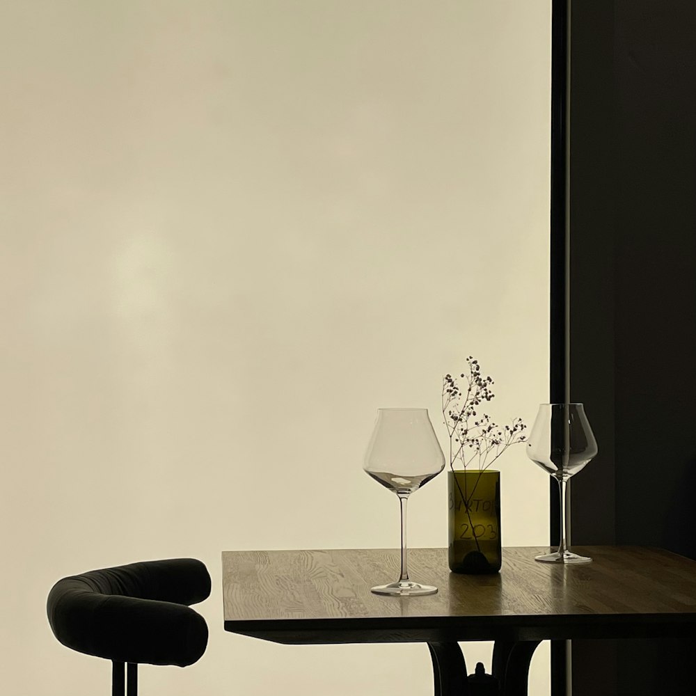 a table with glasses and a vase with flowers on it