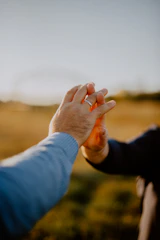 Close-up of hands intertwined during a tender moment outdoors.