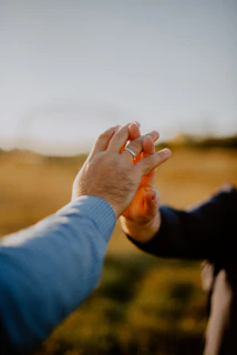 A caregiver gently holding hands with an elderly woman in a sunlit garden.