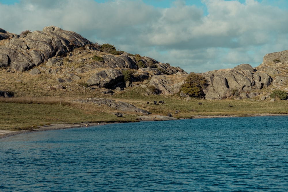 a body of water with a rocky hillside in the background